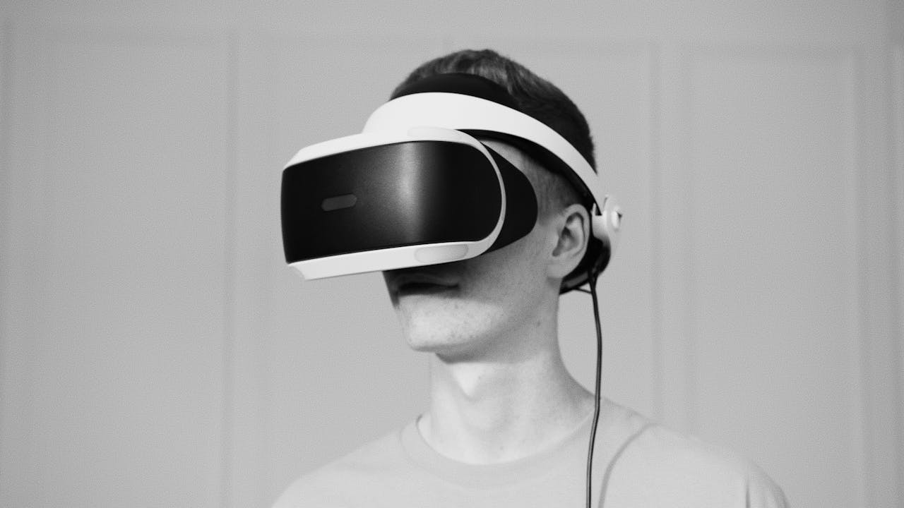 Black and white close-up of a man wearing a virtual reality headset indoors.